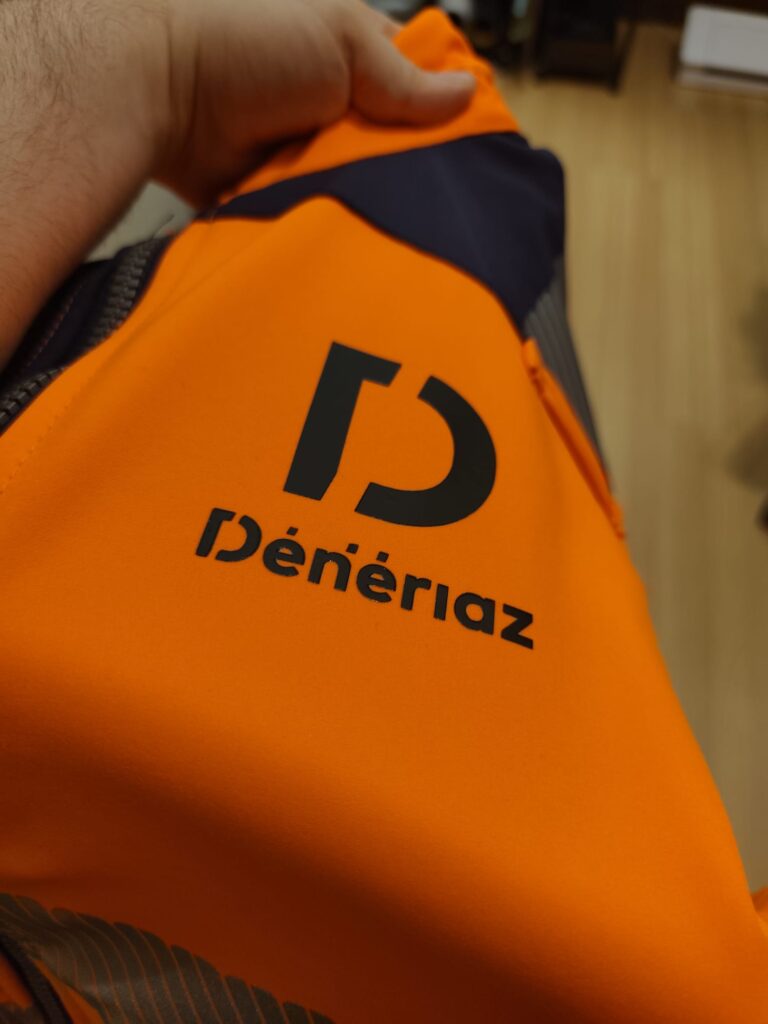 Logo Dénériaz noir sur une veste de travail orange
