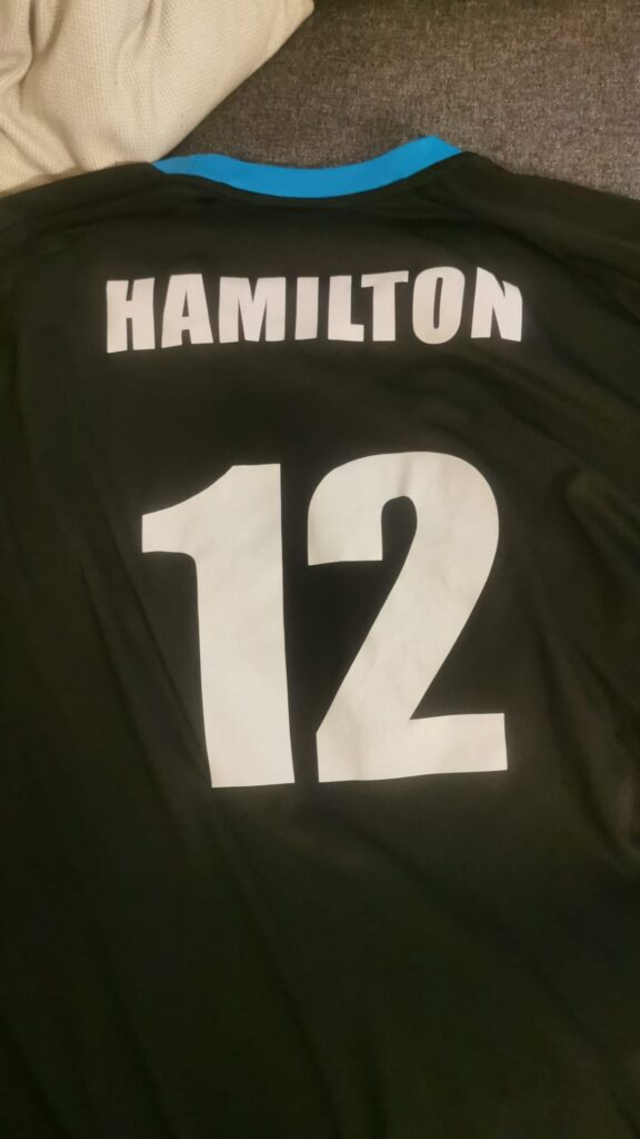 Dos de maillot noir et turquoise marqué Hamilton et numéro 12